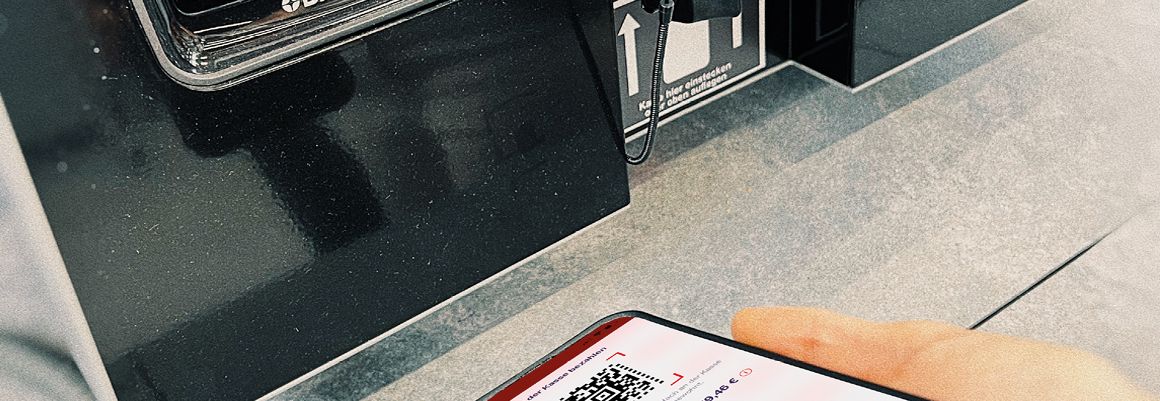 Person scannt QR-Code auf Smartphone an einem Kassenterminal
